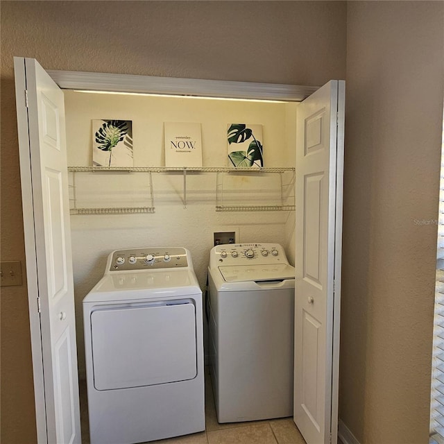 laundry area featuring light tile patterned floors, laundry area, and washer and clothes dryer