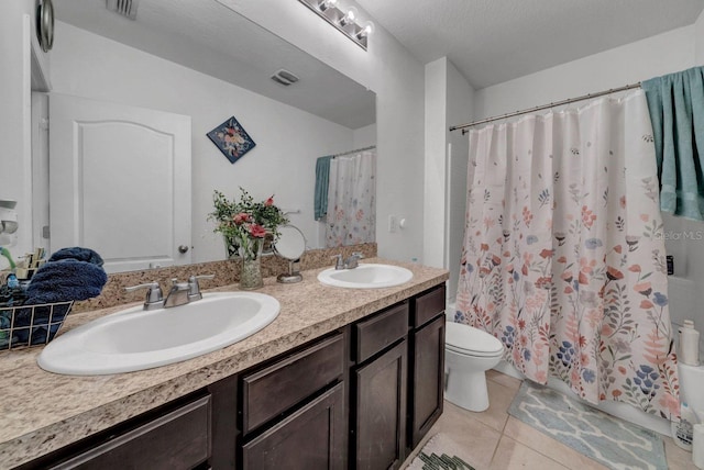 bathroom with vanity, toilet, a textured ceiling, and tile patterned flooring