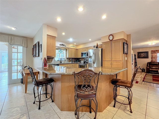 kitchen featuring light tile patterned flooring, stainless steel appliances, a breakfast bar, and kitchen peninsula