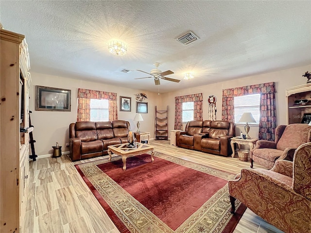 living room with hardwood / wood-style flooring, a healthy amount of sunlight, a textured ceiling, and ceiling fan