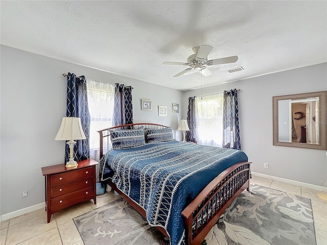 tiled bedroom with ceiling fan and a textured ceiling