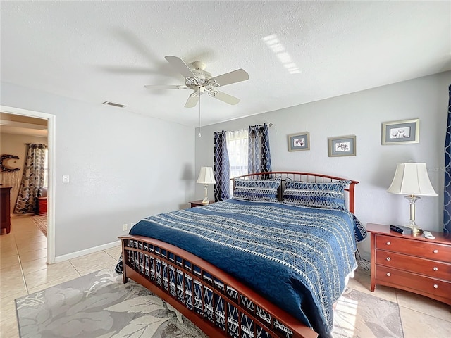 bedroom featuring ceiling fan, a textured ceiling, and light tile patterned floors