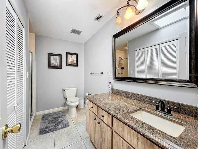 bathroom with a skylight, vanity, a shower, tile patterned floors, and toilet