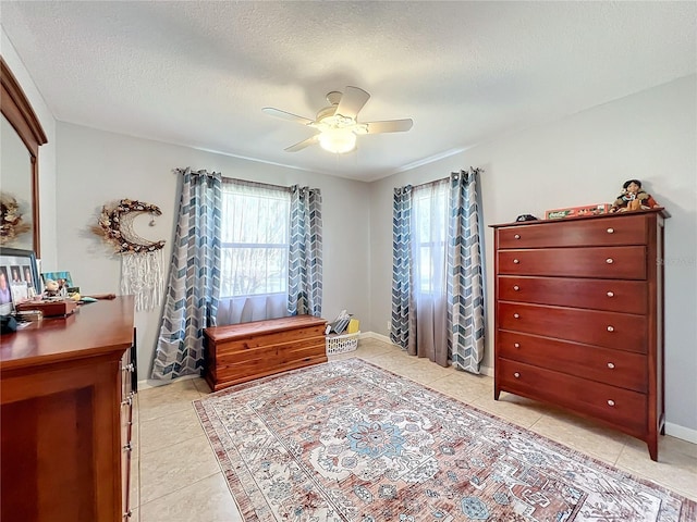 tiled bedroom with ceiling fan and a textured ceiling