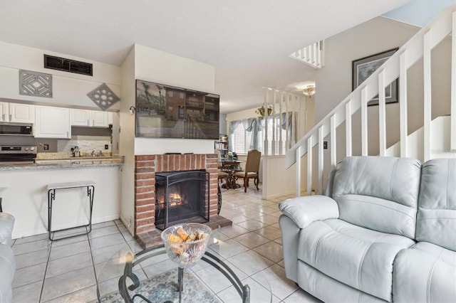 living room featuring light tile patterned flooring and a brick fireplace