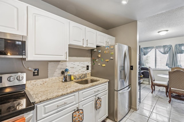 kitchen with sink, a textured ceiling, stainless steel appliances, light stone countertops, and white cabinets