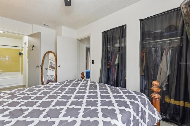 bedroom featuring ceiling fan, ensuite bath, a closet, and a textured ceiling