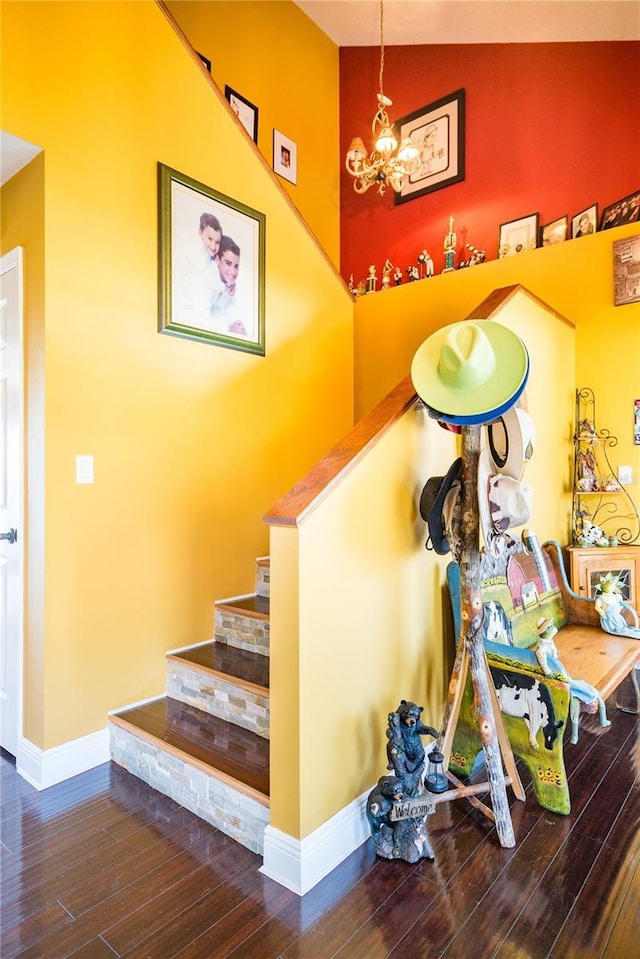 staircase featuring hardwood / wood-style flooring, vaulted ceiling, and an inviting chandelier