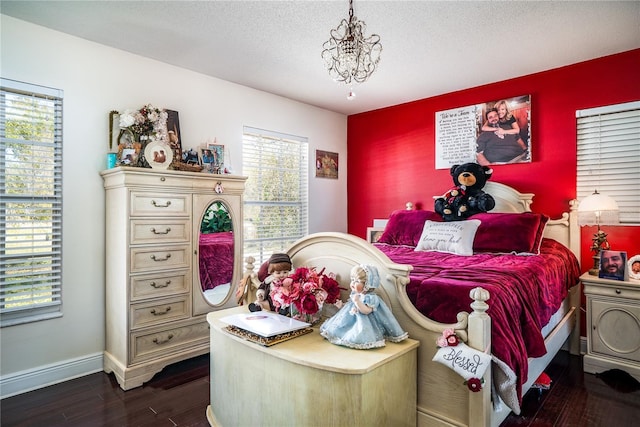 bedroom with a chandelier, a textured ceiling, and dark hardwood / wood-style flooring