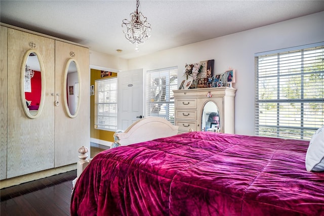 bedroom featuring an inviting chandelier, dark hardwood / wood-style floors, and a textured ceiling