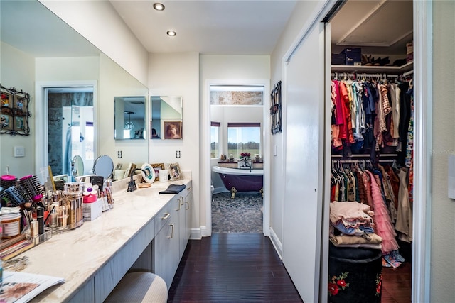 bathroom with vanity, hardwood / wood-style floors, and a tub to relax in