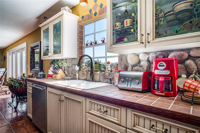 kitchen with sink, stainless steel dishwasher, and tile counters