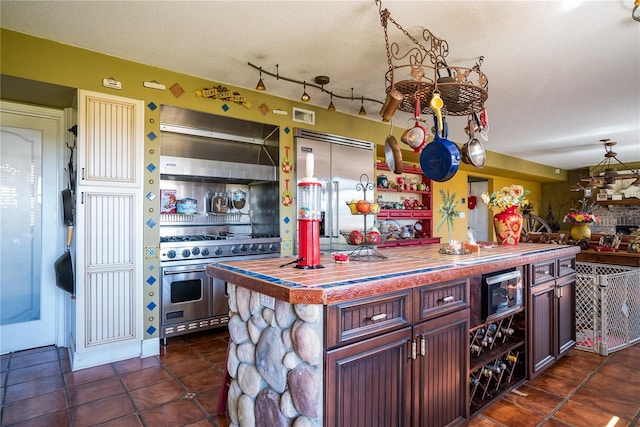 kitchen with a center island, dark tile patterned floors, range hood, and high quality appliances