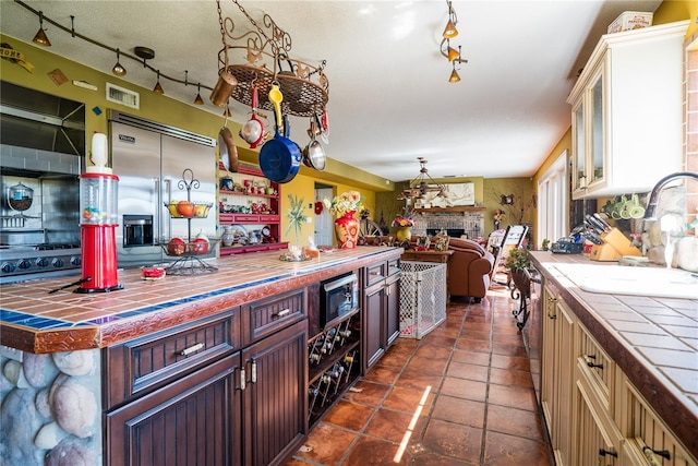 kitchen featuring a fireplace, tile counters, dark tile patterned flooring, and stainless steel appliances