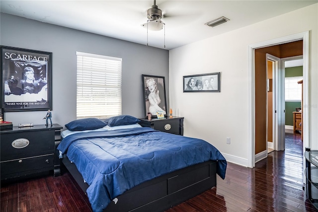 bedroom featuring ceiling fan, dark wood-type flooring, and multiple windows