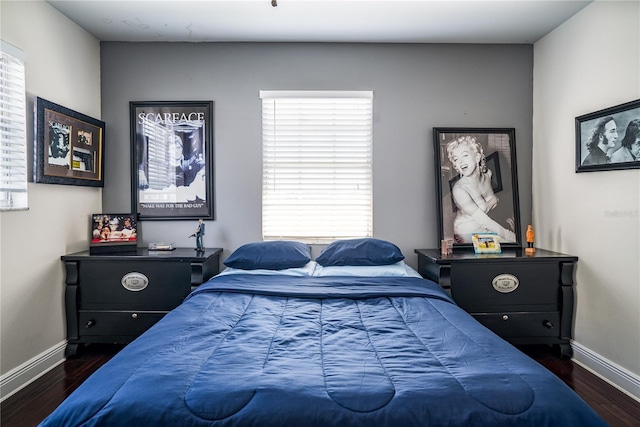 bedroom featuring multiple windows and dark hardwood / wood-style flooring