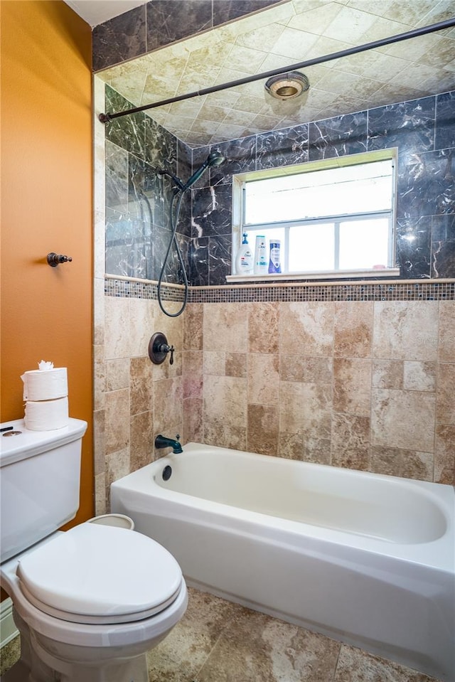 bathroom featuring toilet and tiled shower / bath