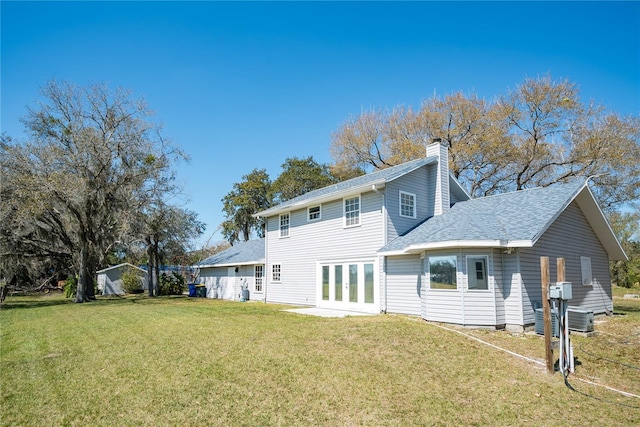 rear view of house with central air condition unit, a lawn, and french doors