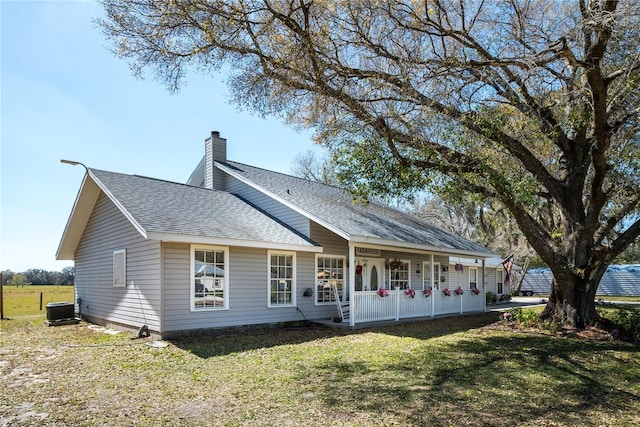 rear view of property with cooling unit and a lawn