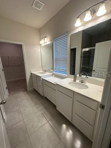 bathroom featuring a shower with door, tile patterned flooring, and vanity