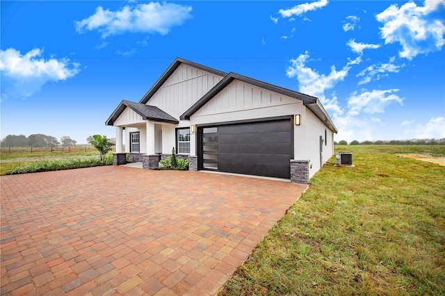 view of front of house featuring a garage, cooling unit, a rural view, and a front lawn