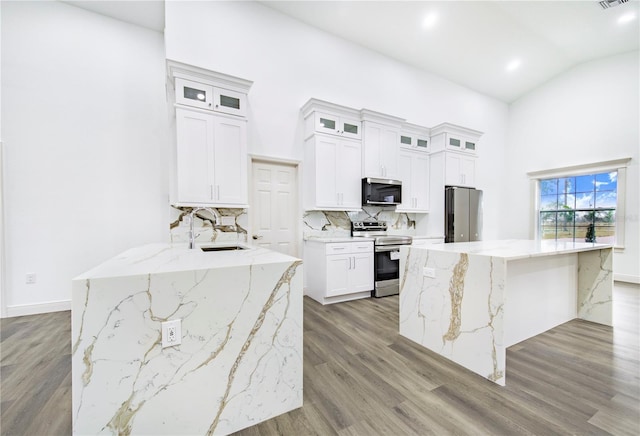 kitchen featuring light stone counters, stainless steel appliances, white cabinets, and a kitchen island