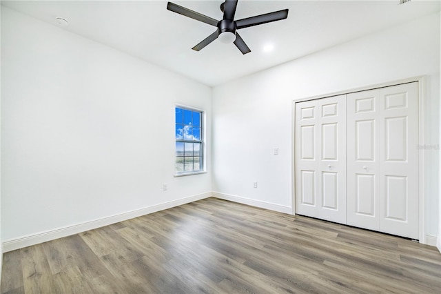 unfurnished bedroom featuring light hardwood / wood-style flooring, ceiling fan, and a closet