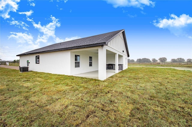 rear view of property featuring a yard, central AC unit, and a patio area