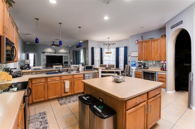 kitchen with appliances with stainless steel finishes, sink, decorative backsplash, hanging light fixtures, and a center island