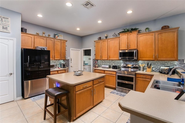 kitchen featuring appliances with stainless steel finishes, sink, light tile patterned floors, and a breakfast bar