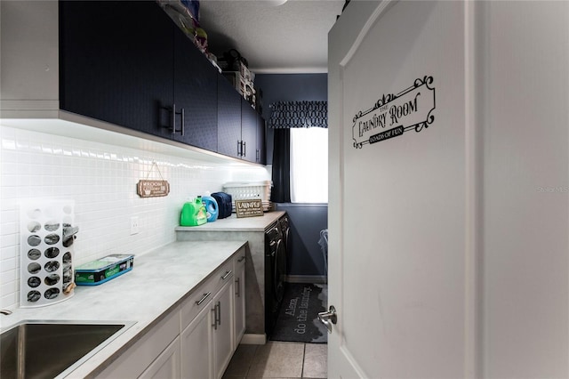 clothes washing area featuring light tile patterned floors, washing machine and dryer, and sink