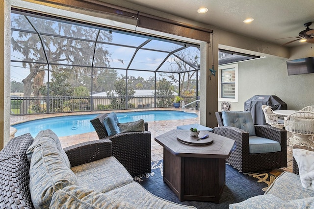 view of swimming pool with ceiling fan, an outdoor living space, grilling area, and glass enclosure