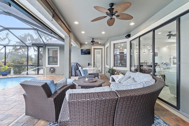 view of patio with area for grilling, an outdoor hangout area, ceiling fan, and glass enclosure