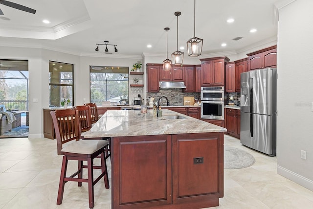 kitchen with sink, a breakfast bar area, a kitchen island with sink, stainless steel appliances, and decorative light fixtures