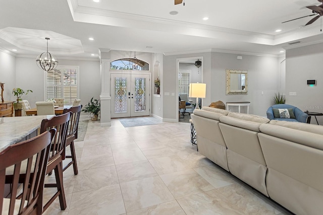 living room featuring french doors, crown molding, ceiling fan with notable chandelier, and a tray ceiling