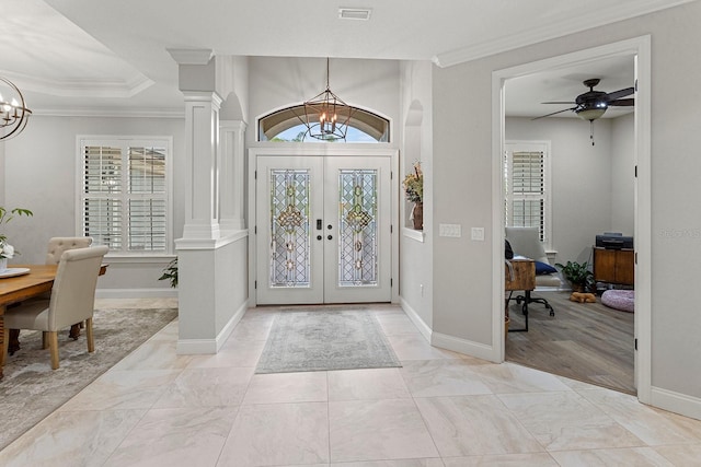 foyer entrance featuring decorative columns, ornamental molding, an inviting chandelier, and french doors