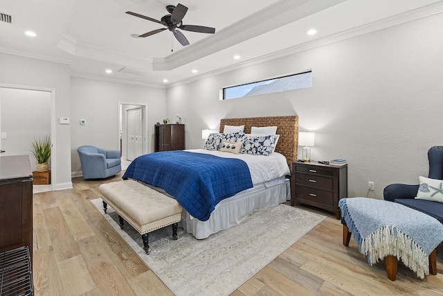 bedroom with ceiling fan, ornamental molding, a raised ceiling, and light hardwood / wood-style flooring