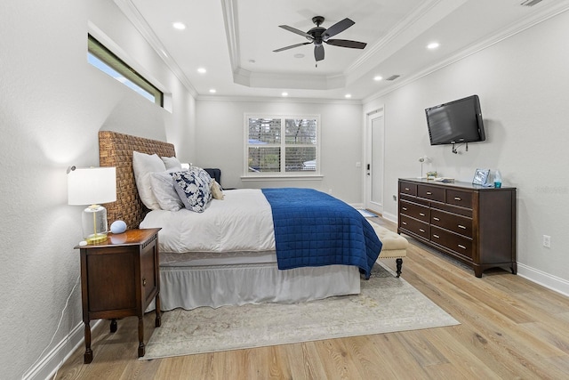 bedroom featuring crown molding, ceiling fan, light wood-type flooring, and a tray ceiling