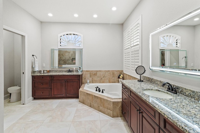 bathroom with vanity and tiled bath