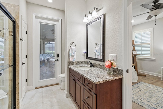 bathroom with ceiling fan, vanity, toilet, and an enclosed shower