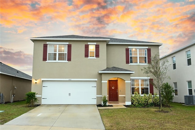 view of front of home with a garage, a lawn, and central air condition unit