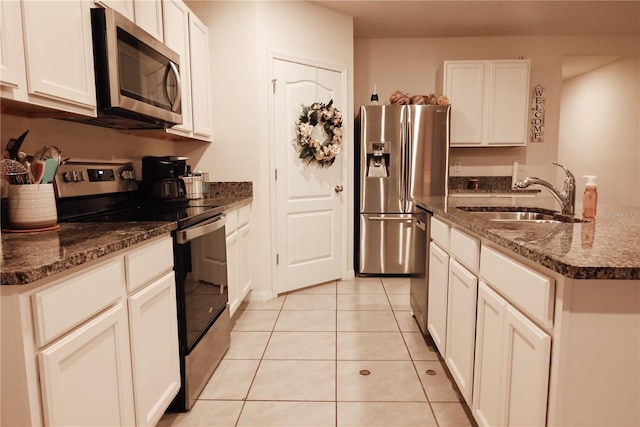 kitchen with sink, light tile patterned floors, appliances with stainless steel finishes, an island with sink, and white cabinets