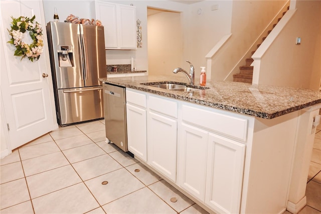 kitchen with light tile patterned flooring, appliances with stainless steel finishes, white cabinetry, an island with sink, and sink