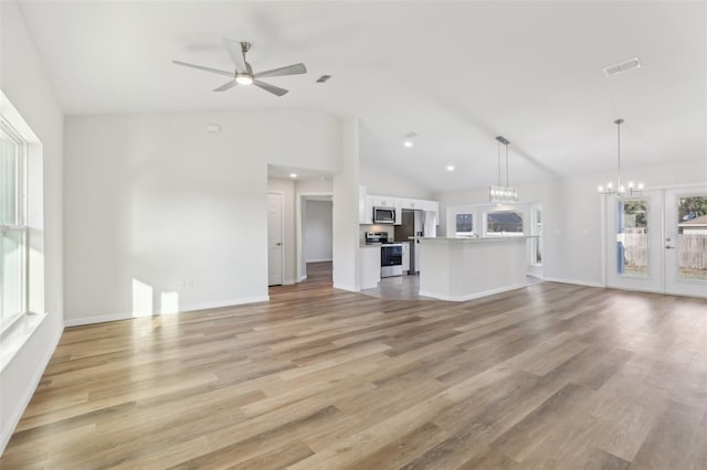 unfurnished living room featuring vaulted ceiling, plenty of natural light, ceiling fan with notable chandelier, and light wood-type flooring