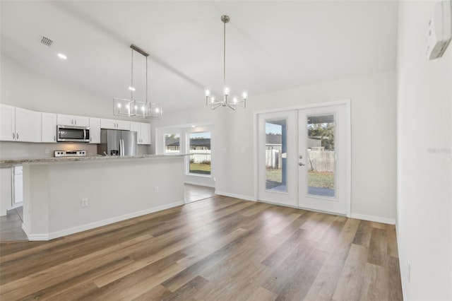 kitchen featuring stainless steel appliances, a wealth of natural light, white cabinets, and decorative light fixtures