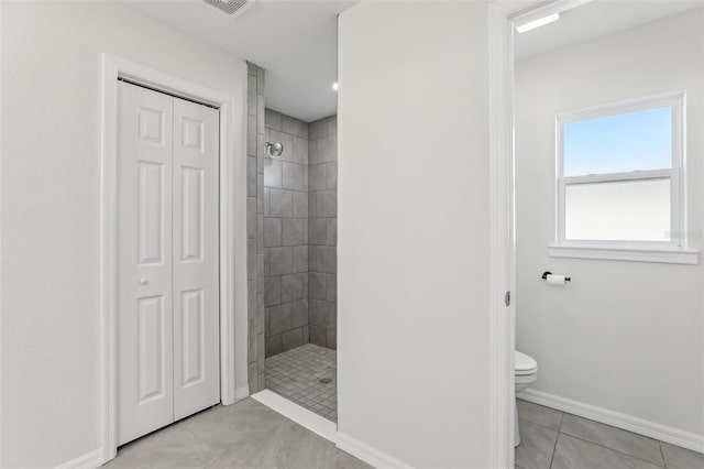 bathroom with tile patterned floors, toilet, and tiled shower