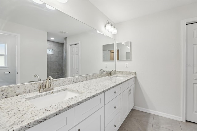 bathroom with tile patterned flooring, vanity, and a tile shower