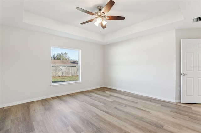 unfurnished room with ceiling fan, a raised ceiling, and light hardwood / wood-style floors