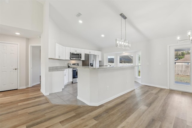 kitchen with white cabinetry, hanging light fixtures, a notable chandelier, stainless steel appliances, and light hardwood / wood-style floors