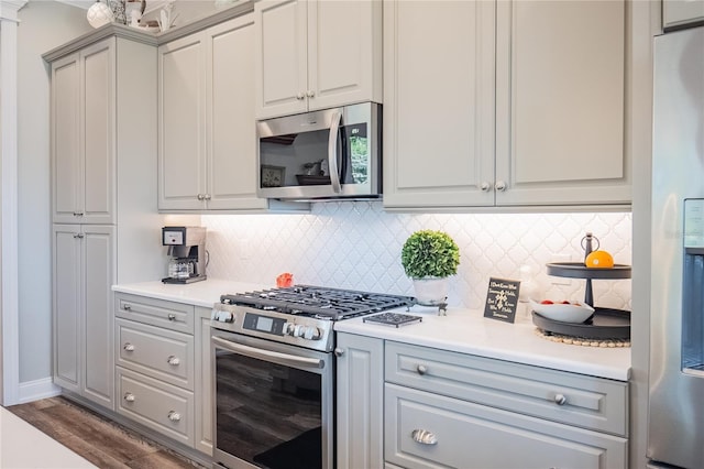 kitchen featuring backsplash, gray cabinets, stainless steel appliances, and dark hardwood / wood-style floors